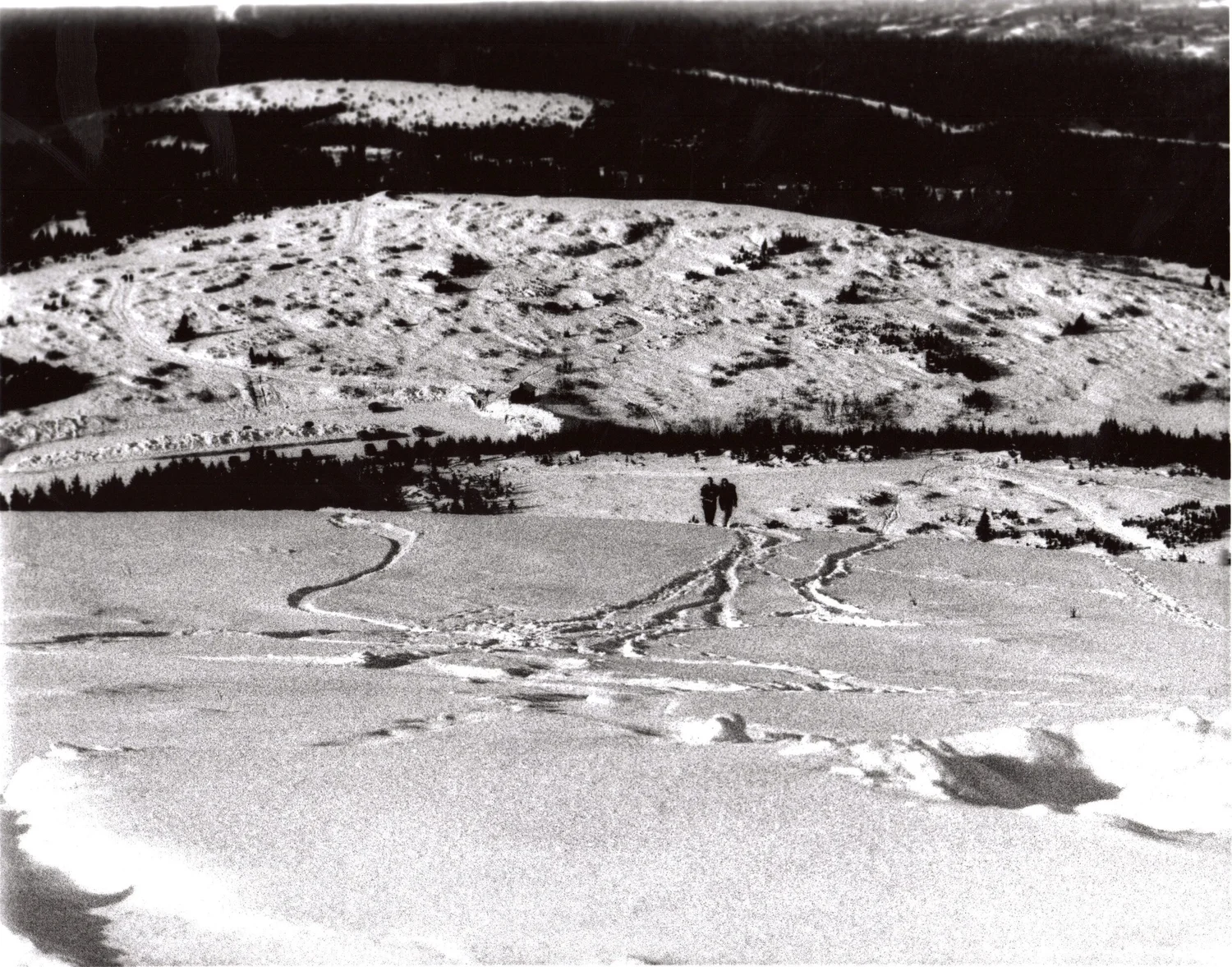 Black and white photograph of figures crossing a snowfield